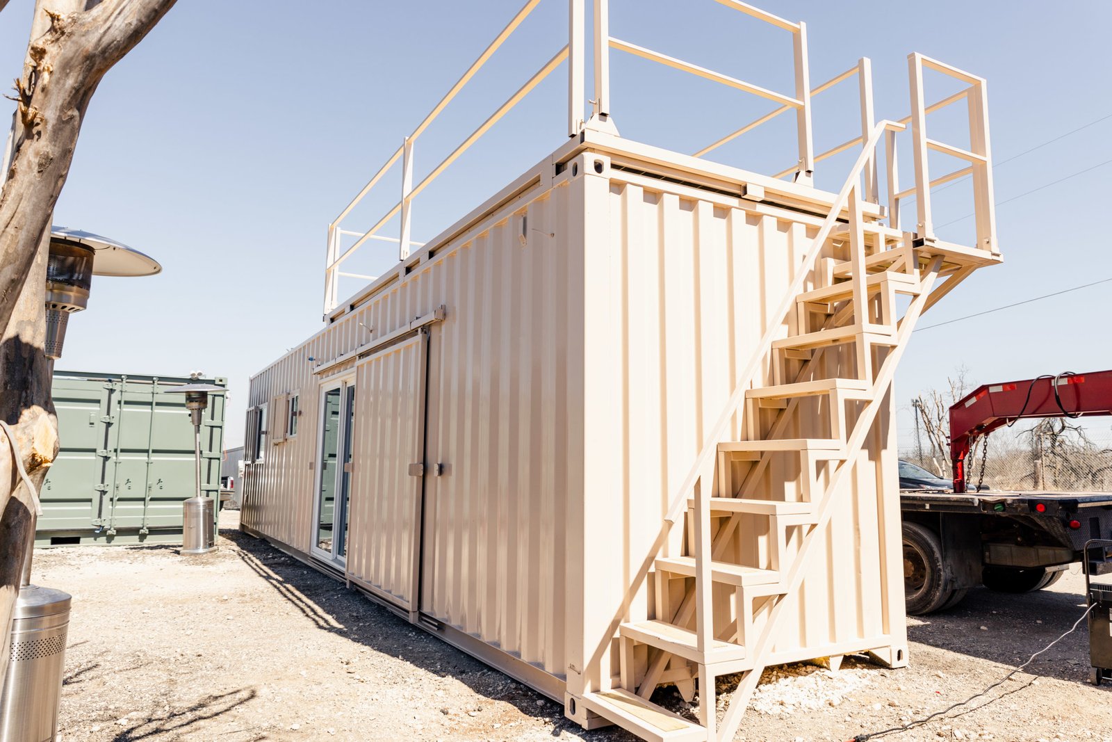 Container home sited on gravel with external staircase and rooftop terrace